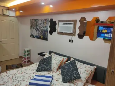 a bedroom with a bed with pillows and a wall at Near Manila Airport, COZY Hotel Style Studio Condo 5G in Manila