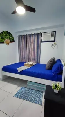 a blue bed in a room with a fan at Near Manila Airport COZY 01 Bedroom Condo - 10L in Manila