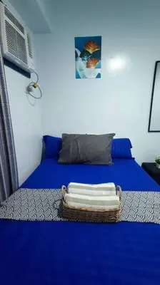a blue bed with a basket of towels on it at Near Manila Airport COZY 01 Bedroom Condo - 10L in Manila