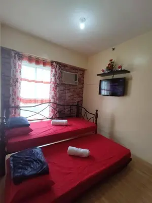 a bedroom with two red beds and a window at Near Manila Airport COZY Studio Condo With Kitchen 11P in Manila