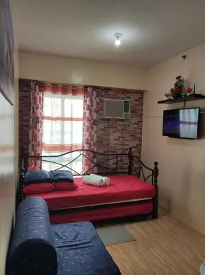 a bedroom with a red bed and a brick wall at Near Manila Airport COZY Studio Condo With Kitchen 11P in Manila