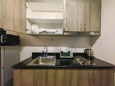 a small kitchen with a sink and a microwave at 1BR Condotel with Balcony at FAME Residences #FM55 in Manila