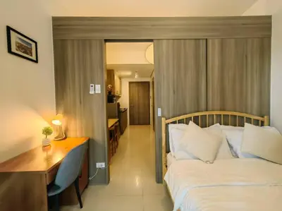 a bedroom with a bed and a desk and a room at 1BR Condotel with Balcony at FAME Residences #FM55 in Manila