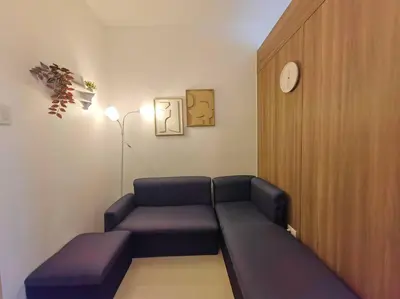 a living room with a couch and a clock on the wall at 1BR Condotel with Balcony at FAME Residences #FM54 in Manila