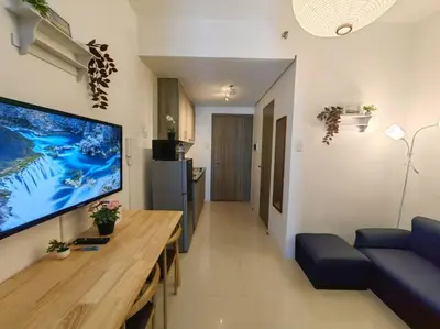 a living room with a large flat screen tv on the wall at 1BR Condotel with Balcony at FAME Residences #FM54 in Manila