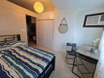 a bedroom with a bed and a table and a desk at Jazz Residences Luxury Staycation in Manila