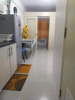 a white kitchen with a table and a refrigerator at Sea Residences Condotel GudStay in Manila