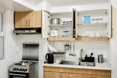 a kitchen with wooden cabinets and a sink at Excellent Location 2 BDRM Homey Wifi Near Airport in Manila