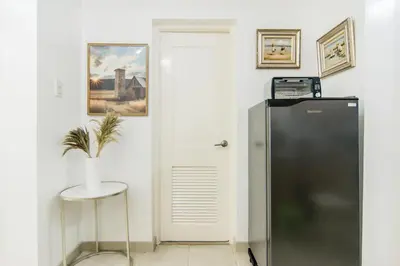 a refrigerator in a room with a table and a stool at Excellent Location 2 BDRM Homey Wifi Near Airport in Manila