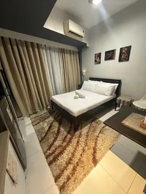 a bedroom with a white bed with a rug at Cozy Room with Citiview at Greenbelt Makati in Manila
