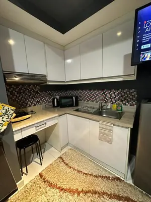 a kitchen with white cabinets and a rug at Cozy Room with Citiview at Greenbelt Makati in Manila