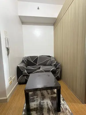 a black leather couch in a living room with a table at Netflix and Chill at Ephra Homestay - Grace Residences Tower 4 in Manila