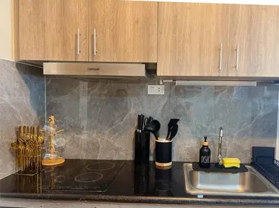 a kitchen counter with a sink and wooden cabinets at 2BR Solana Suite near MOA PICC NAIA in Manila