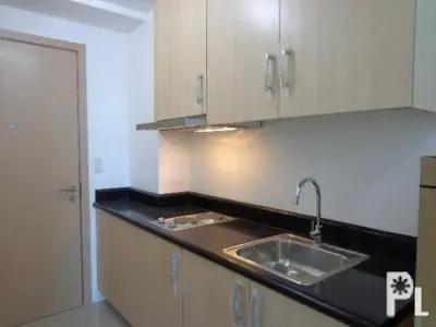 a kitchen with a sink and wooden cabinets at 20th flr SMDC Lights Residence Mandaluyong City Philippines in Manila