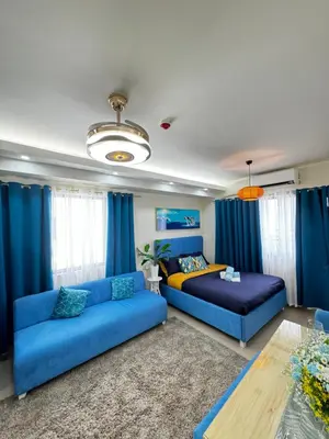 a living room with a blue couch and a bed at Cloud Place Shore 2 Residences in Manila