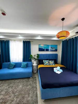 a living room with a blue couch and a bed at Cloud Place Shore 2 Residences in Manila