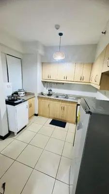 a kitchen with wooden cabinets and a white appliance at Resort-Style 2BR Condo at Alea DMCI Family Staycation in Manila