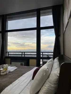 a bedroom with a bed with a large window at Premium Suite with Balcony at The Gramercy Makati Manila in Manila