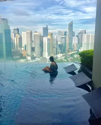 a woman sitting in a pool on top of a city at Premium Suite with Balcony at The Gramercy Makati Manila in Manila