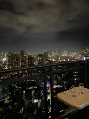 a table with two wine glasses on top of a city skyline at Premium Suite with Balcony at The Gramercy Makati Manila in Manila