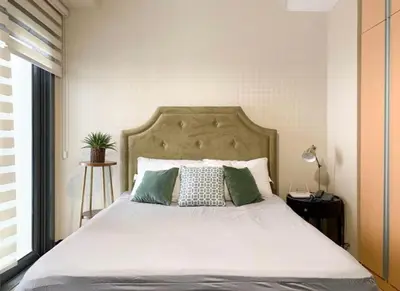 a bedroom with a large bed with green pillows at Deluxe Studio with Balcony at Greenbelt Makati Manila in Manila