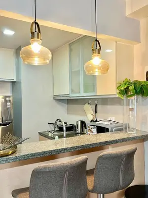 a kitchen with white cabinets and two lights at Deluxe Studio with Balcony at Greenbelt Makati Manila in Manila