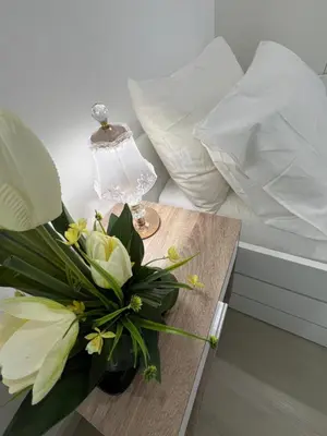 a vase of flowers on a table with a lamp at DT SUITES AND RESORTS at Azure Paranaque in Manila