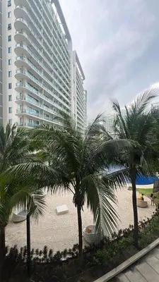 a resort with palm trees in front of a building at DT SUITES AND RESORTS at Azure Paranaque in Manila