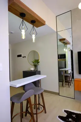 a kitchen with a table and two stools and a mirror at Amelia's Crib at The Verdin in General Trias
