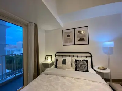 a bedroom with a bed and a large window at Park Mckinley West 1BR Balcony near BGC Makati Airport in Manila