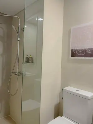 a bathroom with a toilet and a glass shower at Park Mckinley West 1BR Balcony near BGC Makati Airport in Manila