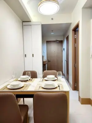 a dining room with a table and chairs with plates and wine glasses at Mocha Flat at Shore 3 Tower 4 in Manila
