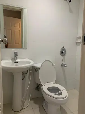 a white bathroom with a toilet and a sink at Hotel Sogo Bacoor in Bacoor