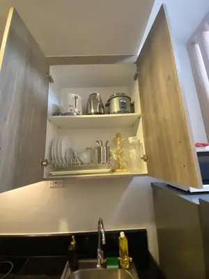 a kitchen with a sink and a shelf with dishes at Coast Residences condo near MOA, StarCity and PICC in Manila