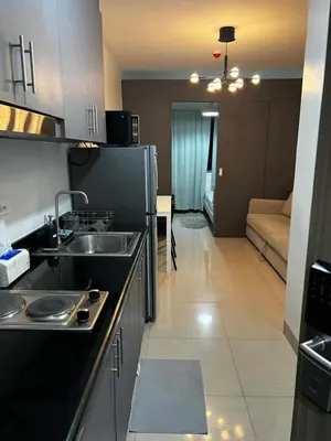 a kitchen with a sink and a living room at 1 BR Apartment near SM Mall of Asia, Airport, Manila in Manila