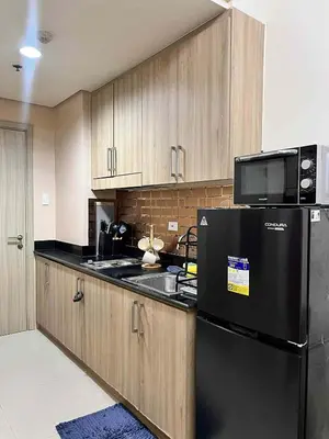 a kitchen with a black refrigerator and wooden cabinets at Espacio Tres in Manila