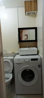 a bathroom with a washing machine and a toilet at Two bed room unit with parking space in Manila