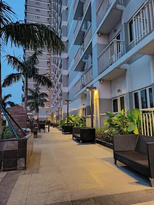 a walkway in a building with benches and palm trees at Coast Residences-Ronnzel staycation in Manila