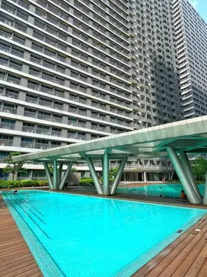a large building with a swimming pool in front of it at BALAY MULANO at FAME RESIDENCES MANDALUYONG CITY l with balcony pool view l 200mbps wifi in Manila