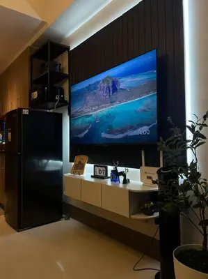 a black refrigerator and a tv on a wall at BALAY MULANO at FAME RESIDENCES MANDALUYONG CITY l with balcony pool view l 200mbps wifi in Manila