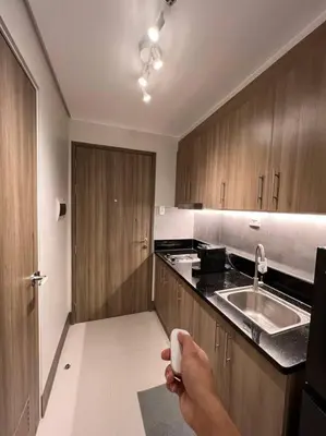 a person holding a remote control in a kitchen at BALAY MULANO at FAME RESIDENCES MANDALUYONG CITY l with balcony pool view l 200mbps wifi in Manila
