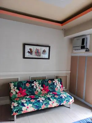 a living room with a couch with flowers on it at Room Across NAIA Terminal 3 Two palm tree in Manila