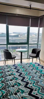 two chairs and a table in a room with windows at Room Across NAIA Terminal 3 Two palm tree in Manila