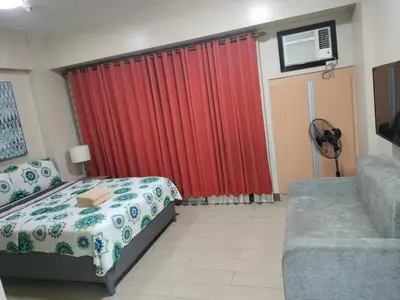 a bedroom with a bed and a couch and a red curtain at Room Across NAIA Terminal 3 Two palm tree in Manila