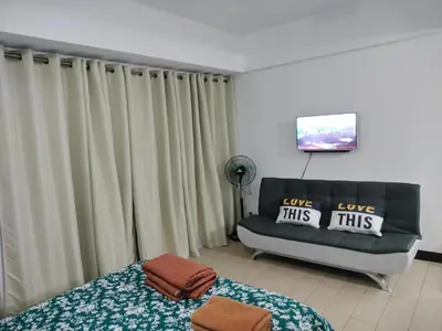 a bedroom with a bed and a couch and curtains at Room Across NAIA Terminal 3 Two palm tree in Manila