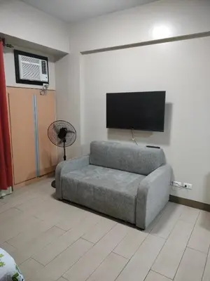 a living room with a couch and a flat screen tv at Room Across NAIA Terminal 3 Two palm tree in Manila