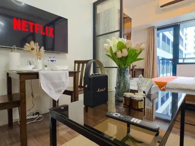 a living room with a table with a vase of flowers at 1BR Makati, Air Residences M008 in Manila