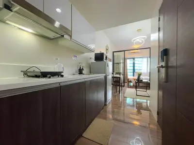 a kitchen with wooden cabinets and a dining room at 1BR Makati, Air Residences M008 in Manila