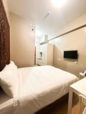 a bedroom with a white bed and a television at S&Rs Place Space taft condominium in Manila