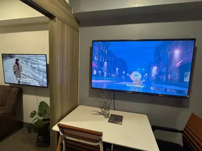 a room with a table and a large tv on a wall at Fame Residences Mandaluyong 1 BR with two Big TV with Balcony in Manila